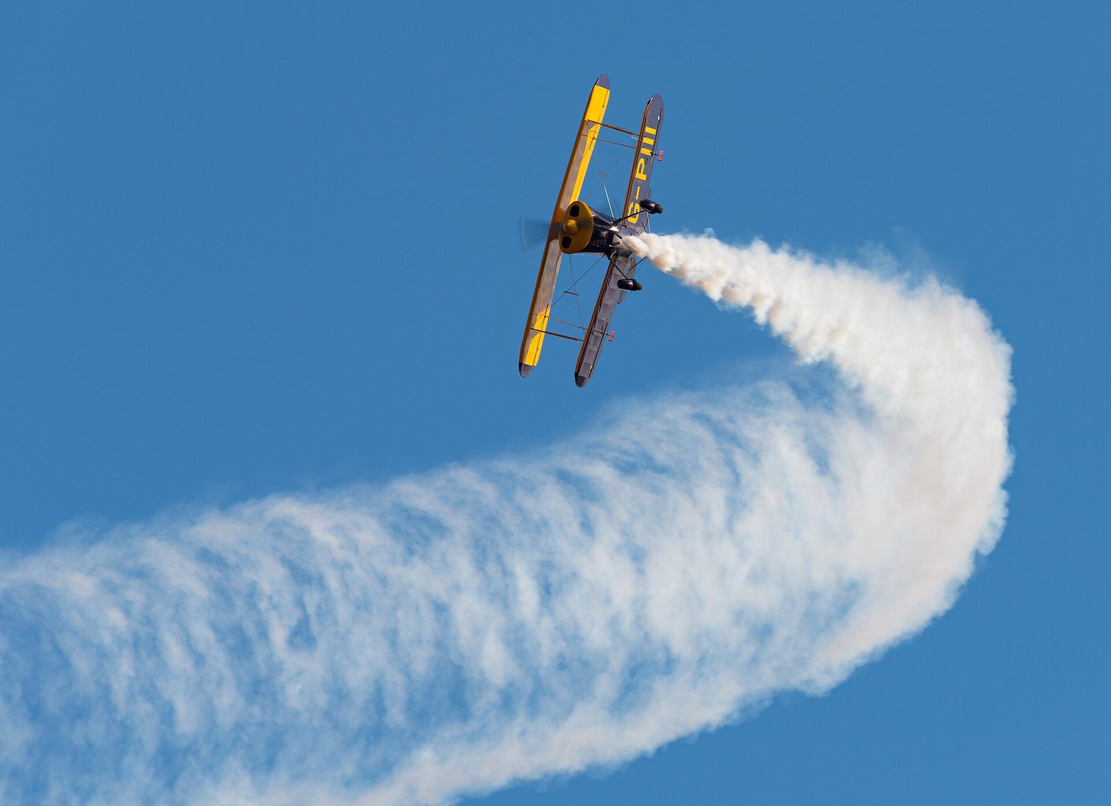 A Pitts aerobatic biplane trailing smoke